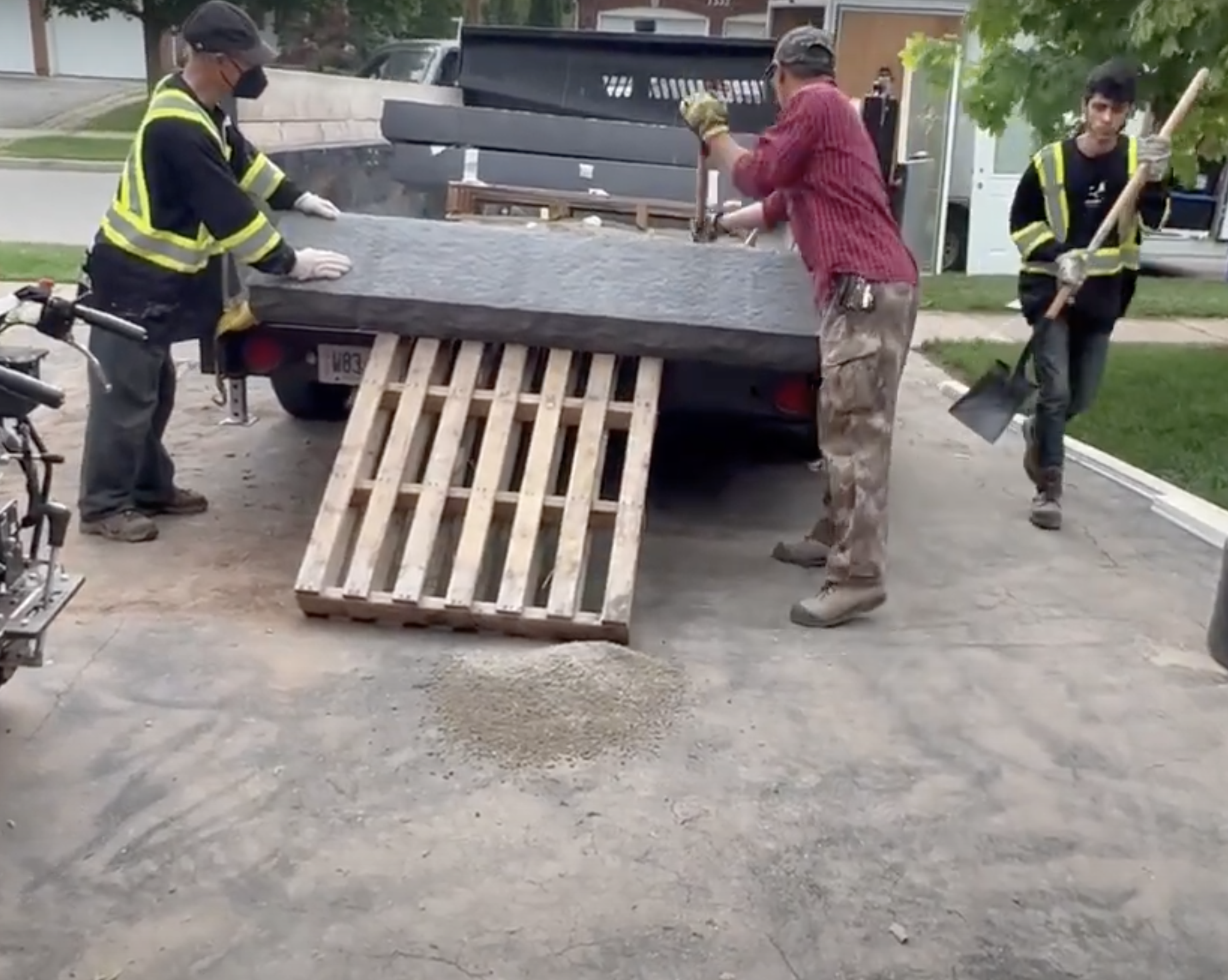 workers unloading heavy step stones off a truck without heavy machinery